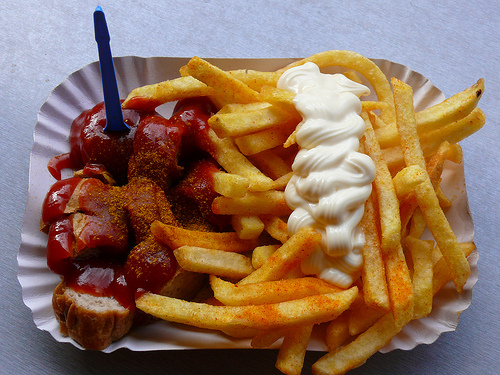 Currywurst.  The sausage (wurst) can either be Weiß (white) or Rot (red). The wurst is cooked, sliced and covered in a ketchup type sauce, then sprinkled with curry powder. It is served temperature hot, but I do not find it that spicy.  Typically, currywurst is served with french fries (pommes frites) ...note that in Germany, fries typically come with mayonnaise and  not ketchup.  Then, to eat it, you are given a very small wooden or plastic stick with two prongs on the end. This is THE MOST POPULAR fast food in Germany